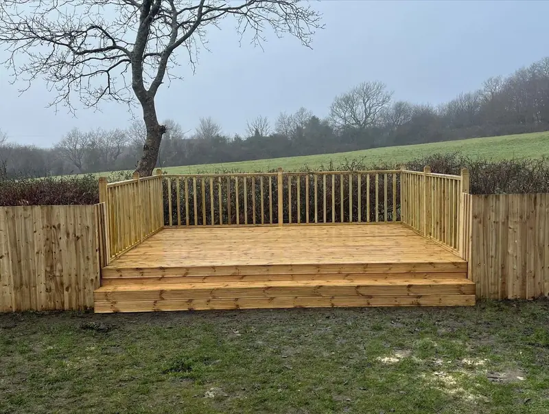 Raised timber deck with spindle balustrade and wide steps, set against new fencing and fields