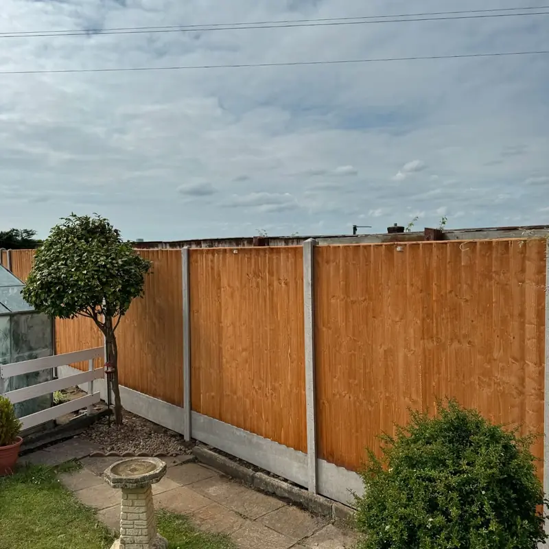 Orange-brown fence panels between grey concrete posts and gravel boards around a lawn