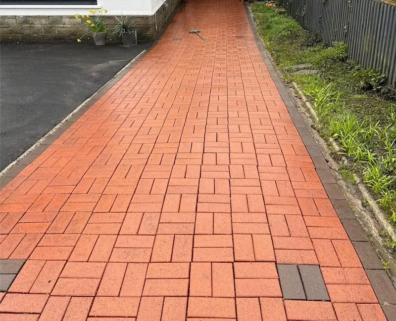 Red block paving path to a garage, bright and clean after power washing